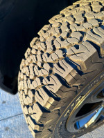 Close-up of BF Goodrich All Terrain A/T K02 tire tread on 2015 Jeep Cherokee Limited with rugged design.