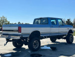 1995 Ford F350 Quad Cab 4WD with a monster lift and new tires, showcasing its rugged design.