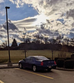 2006 Monte Carlo parked, showcasing its blue color and nearby landscape with cloudy skies.