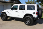 2018 Jeep Wrangler Sahara in white with aftermarket wheels and tires, parked in a driveway.