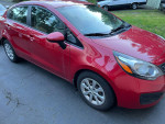 2013 Kia Rio in red color parked, featuring khaki fabric interior and automatic transmission.