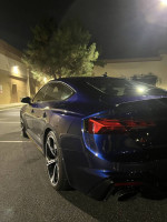 2021 Audi RS 5 Sportback in blue parked at night, showcasing sleek design and premium features.