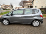 2013 Honda Fit in grey color, side view, with low mileage and excellent fuel efficiency for sale.