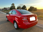 2018 Chevrolet Sonic LT in red, parked on a road with a scenic background, showcasing a stylish exterior.