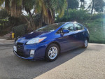 2011 Toyota Prius One in blue with gray interior parked in a scenic area, showcasing its design and alloy wheels