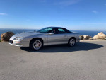 2002 Chevrolet Camaro SS in silver with T-top, parked near the ocean, showcasing its sporty design and features.