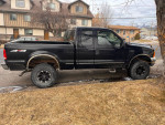 1999 Ford F350 Super Duty Crew Cab parked, featuring manual transmission and rugged tires for durability.