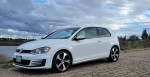 2015 Volkswagen GTI 2dr parked by a lake, showcasing its sleek design and sporty features.