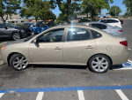 2010 Hyundai Elantra in gold color parked, showcasing its sleek design and fuel-efficient features.