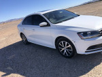 2018 Volkswagen Jetta white sedan with black rims parked in a desert landscape