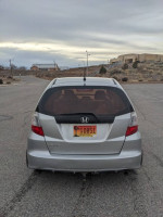 Rear view of a 2013 Honda Fit parked in a spacious area, showcasing its sleek design and custom hitch.