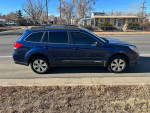Side view of a blue 2011 Subaru Outback with all-wheel drive, parked on the street.