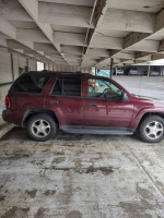 2006 Chevrolet Trailblazer parked under a structure, showing its red exterior and well-maintained condition.