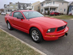 2007 Ford Mustang in red, with premium package and winter tires, parked on a residential street.