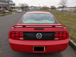 Rear view of a red 2007 Ford Mustang with cosmetic imperfections parked on a street