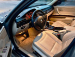 Interior view of a 2011 BMW 328xi with beige leather seats and dashboard lights illuminated.