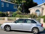 2024 Chevrolet Malibu in silver parked on the street, showcasing its clean exterior and strong design.