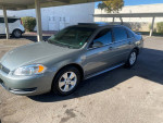 2009 Chevrolet Impala LT FWD in silver with tinted windows parked in a carport.