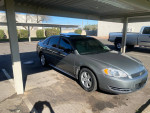 2009 Chevrolet Impala LT in silver parked under a canopy, showcasing its sleek design and good condition.