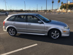 2003 Mazda Protege 5 parked, featuring silver color, 135k miles, auto transmission, sunroof, with minor body blemishes.