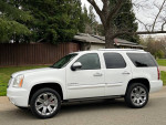 2007 GMC Yukon Denali AWD in white, showcased with chrome wheels, parked in a residential area.