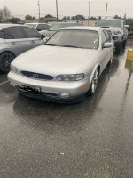1996 Infiniti J30 RWD in silver parked in a lot, showcasing its clean design and distinctive features.