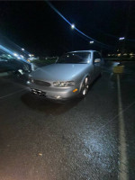 1996 Infiniti J30 RWD parked at night, showcasing its sleek design and stock G37 wheels.