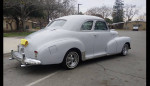 Classic 1947 Chevy Fleetmaster coupe in gray primer parked on the street with a towel on the rear.