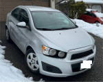 2012 Chevrolet Sonic in immaculate condition parked in snow, showcasing its well-maintained exterior.