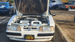 1989 Ford Mustang LX 5.0 with open hood showcasing clean engine and original parts at car show.