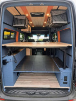 Interior view of a 2023 Mercedes-Benz Sprinter van with wooden shelving and modern design features.