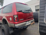 2000 Ford Excursion with red exterior and tan interior, parked in towing yard. Vehicle has minor dents and scratches.