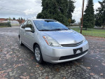 2006 Toyota Prius with low mileage and hybrid battery warranty parked on a gravel road.