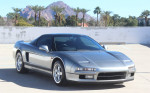 1991 Acura NSX in silver color, showcasing its sleek design and sporty features against a clear background.