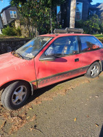 1990 Geo Metro for sale with salvage title, showing worn exterior and replaced parts from Suzuki Swift.