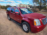 2013 GMC Yukon XL SLT RWD in red on a gravel road, showcasing its spacious design and luxury features.