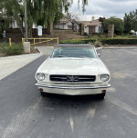 Front view of a white 1965 Ford Mustang convertible, showcasing its classic design and excellent condition.