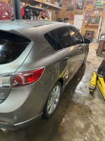2011 Mazda 3 s Sport Hatchback in a garage, featuring custom black wheels and tinted windows.
