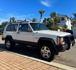 1993 Jeep Cherokee Sport parked on the street, showcasing its classic design and maintained condition.