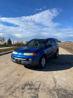 2004 Saturn VUE blue sport utility vehicle parked on a dirt road under a clear blue sky.