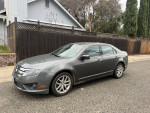 2010 Ford Fusion sedan in gray color parked on the street, showcasing its sleek design and new tires