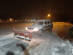 2002 Jeep Grand Cherokee with snow plow parked in snowy driveway at night