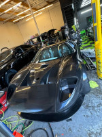 Close-up of a custom 2024 Ford GT in a garage, showcasing its sleek black design and racing features.