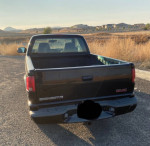 1999 GMC Sonoma SLS Sport 4WD truck parked in a rural area, showing the back and bed of the vehicle.