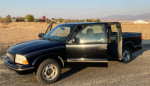 1999 GMC Sonoma SLS Sport 4WD parked, showing a black exterior with an open door, ideal for buyers seeking repairs.