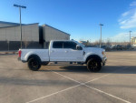 2017 Ford F350 Powerstroke 4x4 Lariat in parking lot, showcasing sleek design and black wheels.