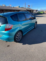 2013 Honda Fit Sport in turquoise color parked in a lot, showcasing its hatchback design and sporty features.